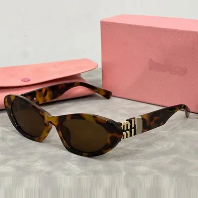 Tortoiseshell cat-eye sunglasses with brown lenses, resting beside a pink case.
