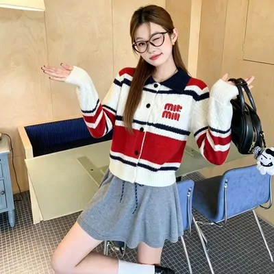 A striped red and white knit cardigan worn over a grey pleated skirt.